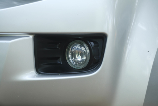Closeup modern white sports car front left blinker, full frame horizontal composition with copy space