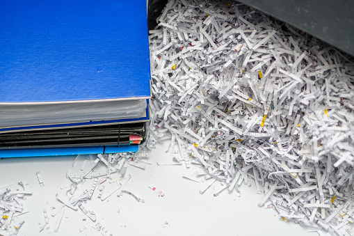 Destroyed corporate office documents, cut into strips of paper in a shredder closeup