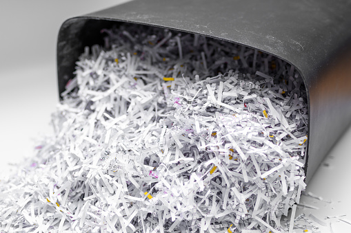 Destroyed corporate office documents, cut into strips of paper in a shredder closeup