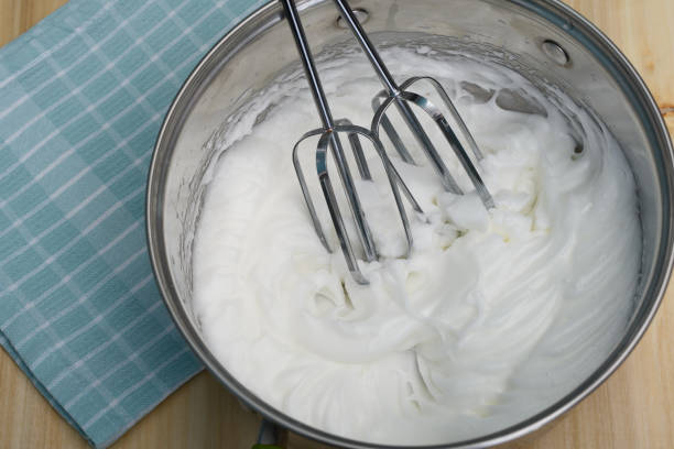 Whipped egg white foam for meringues, close-up isolated in a pot