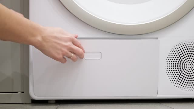 A housewife inserts a cleaned filter into an automatic dryer. Maintenance machine after using. Housework in home laundry. Close-up view. Slow motion. High quality 4k footage