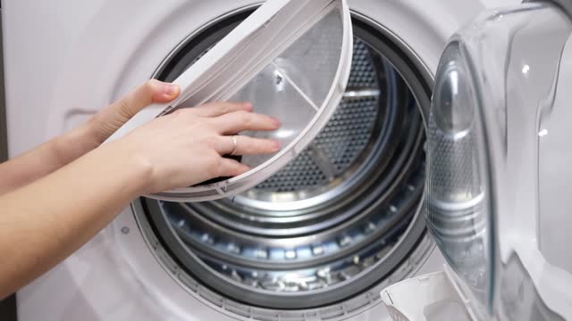 Housewife cleans up lint, dirt and dust from tumble dryer filter. Maintenance machine after using. Close-up. Slow motion. High quality 4k footage