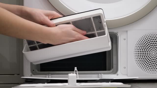 Housewife cleans up lint, dirt and dust from tumble dryer filter. Maintenance machine after use the machine. Close-up. Slow motion. High quality 4k footage