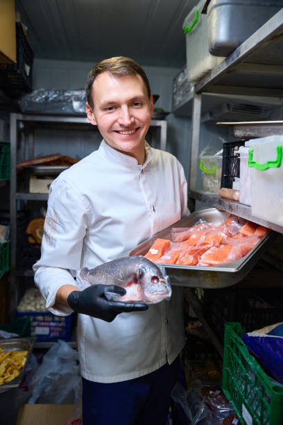 happy chef holding big fish isolated on white