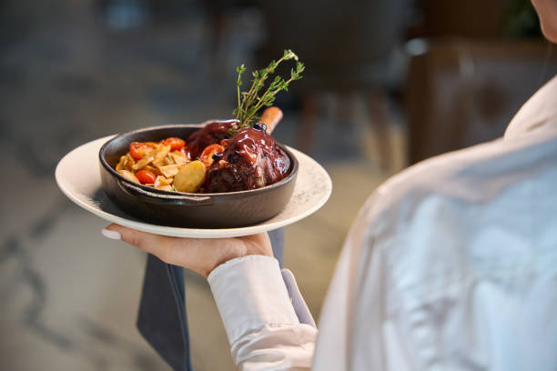 istock Waitress serves meat with vegetables in a serving pan 1949377300