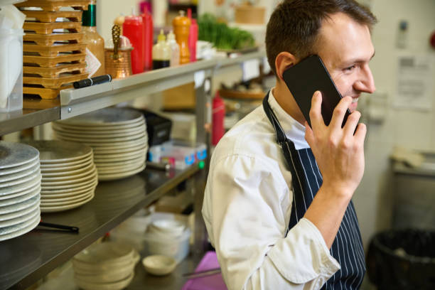 istock Cook in a chefs apron communicates on his mobile phone 1949377851