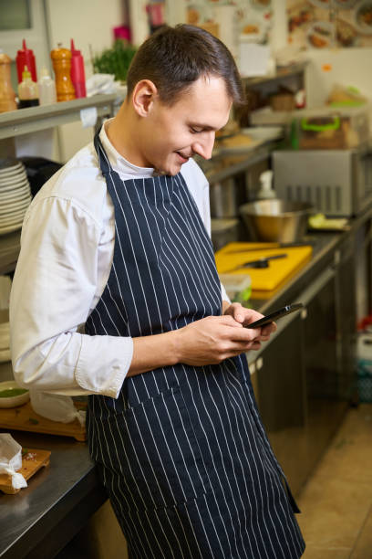 istock Guy in a chefs apron communicates on his mobile phone 1949377852