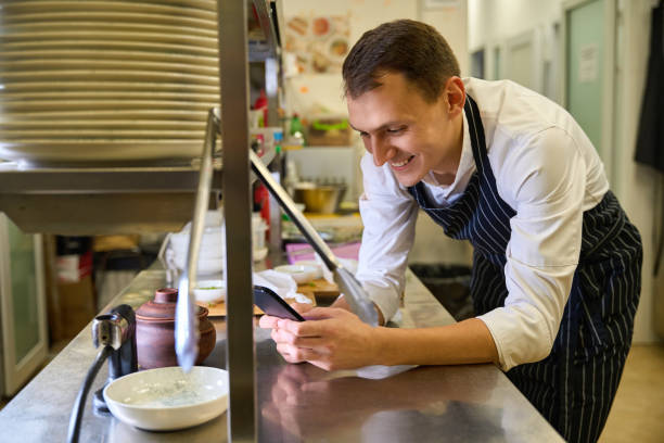 istock Cook at the kitchen rack communicates on his mobile phone 1949377856
