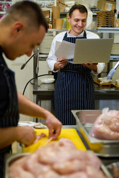 istock Chef is sitting with work papers and laptop in restaurant kitchen 1949377857