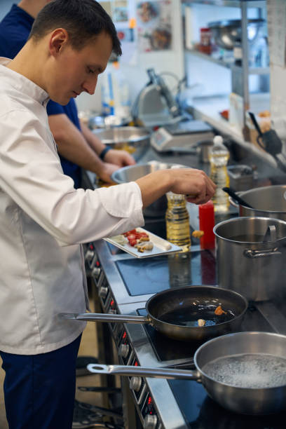 istock Kitchen employee cooks on a frying pan 1949385170
