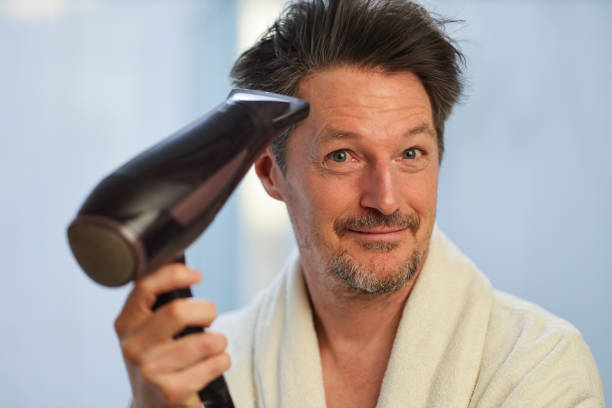 istock Mature man blow drying his hair 1949399215