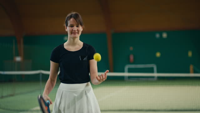 SLO MO Smiling Young Female Player Bouncing Tennis Ball on Racket in Sports Club