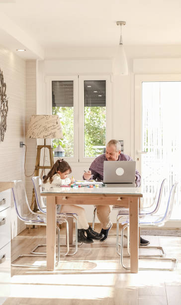 istock Girl playing while her grandfather working next to them 1949410654