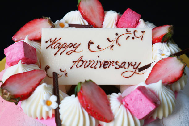 Closeup of white chocolate anniversary greeting card on top of strawberry mousse cake