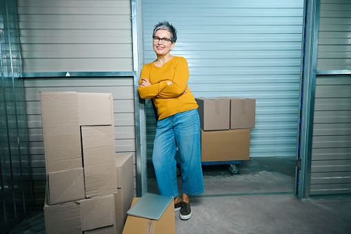 Lady stands leaning on the wall near the entrance to a container in a storage warehouse