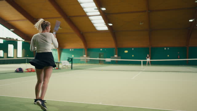 SLO MO Rear View of Active Young Female Tennis Player Hitting Ball with Racket on Court in Sports Club