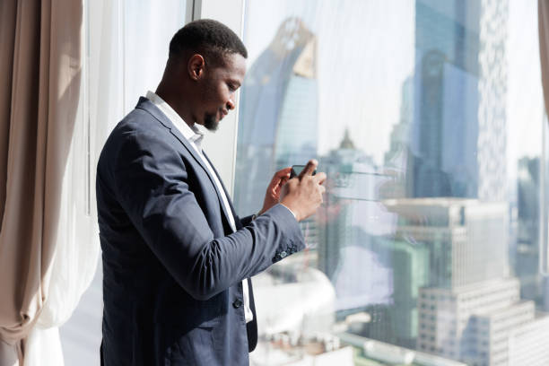 istock Black people businessman using mobile phone beside window in the room 1949434755