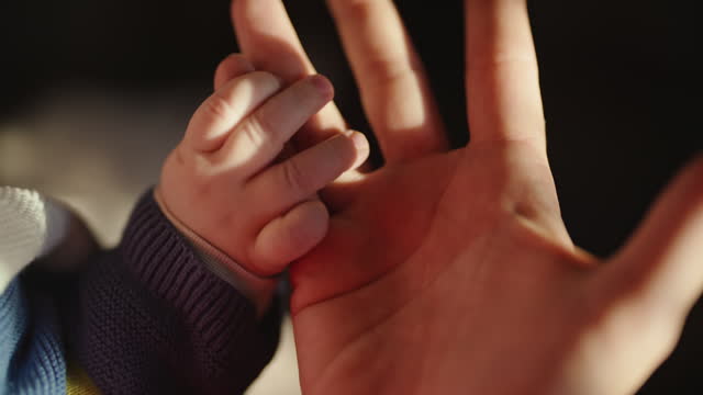 SLO MO Cropped Handheld Shot of Baby Boy Holding Father's Finger at Bright Home