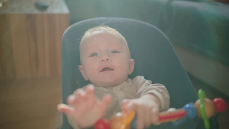 SLO MO Handheld Shot of Cheerful Baby Boy Rocking on Baby Bouncer at Bright Home