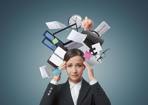 Businesswoman with a collage of business items and office supplies around her head, brain overload and stress concept