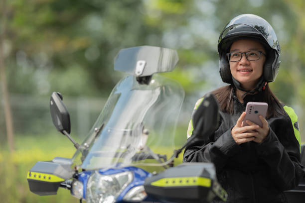 Asian female biker using smart phone searching next destination and weather before start journey