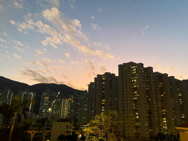 The image captures the serene moment of sunset, where the golden hues of the setting sun illuminate the sky and cast a warm glow on a cluster of tall residential buildings.