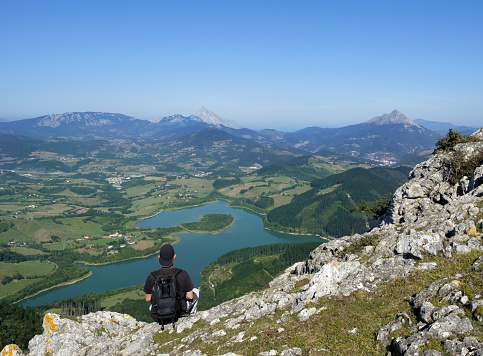Hiker at the top of Mount Orkatzategi and Urkulu reservoir in the background, Euskadi