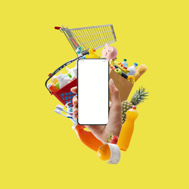 istock Hand holding a smartphone with blank screen and groceries 1949495330