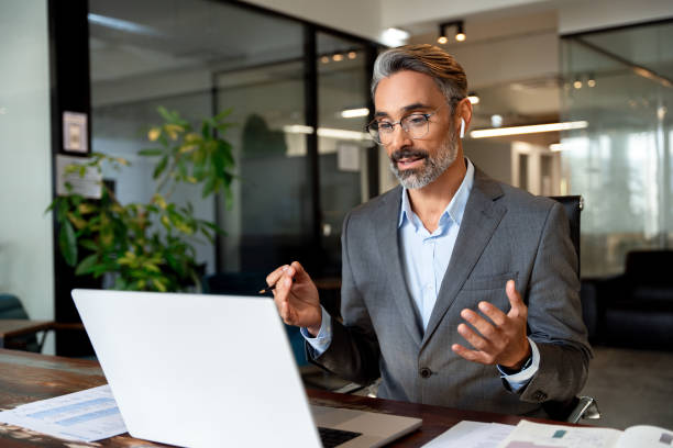 istock Middle-age Hispanic man using computer remote for business studying, watch online virtual webinar training meeting, video call. Smiling mature Indian or Latin businessman working on laptop in office. 1949502323