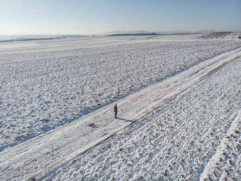 Man walking in the road covering with snow.