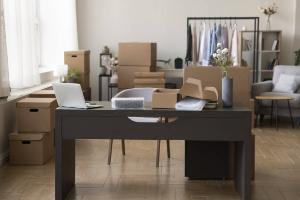 istock Workplace with desk and heap of cardboard boxes 1949507071