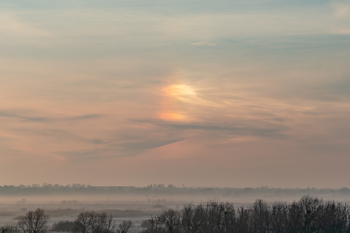 A parhelion (plural parhelia) in meteorology, is an atmospheric optical phenomenon that consists of a bright spot to one or both sides of the Sun. This phenomenon also has names: sun dog (or sundog) or mock sun, also called