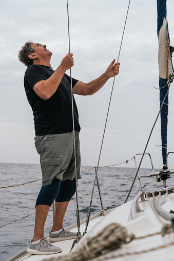 Sailor holding the ropes on a sailboat by the Mediterranean Sea in a cloudy day