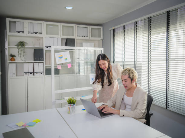 istock Two young Asian people colleagues working together and using laptop computer while discussing on new project at modern office 1949521878