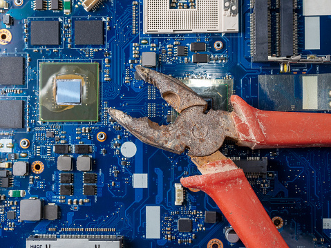 Computer repair concept. Old rusty passages on a blue laptop motherboard. The concept of unskilled work