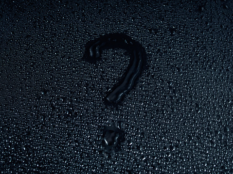 question mark written on a surface made of drops on a black background.
