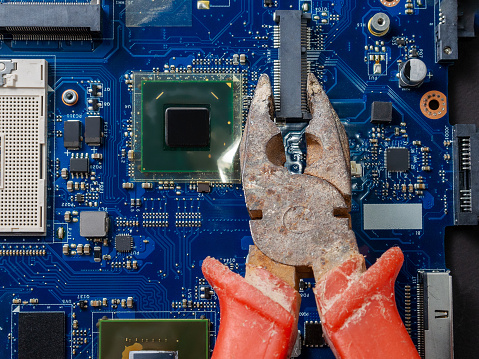 Computer repair concept. Old rusty passages on a blue laptop motherboard. The concept of unskilled work