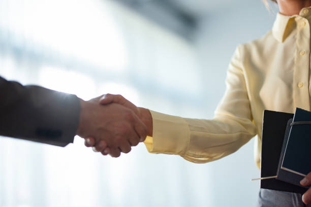 Zoomed in photo of two unrecognizable businesspeople, a man and a woman, shaking hands.
