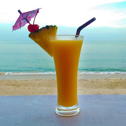 Fresh orange cocktail on wooden table. Blur beach on background