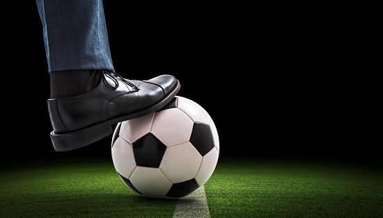 Professional coach with one foot on the soccer ball, sports and soccer championships concept, copy space