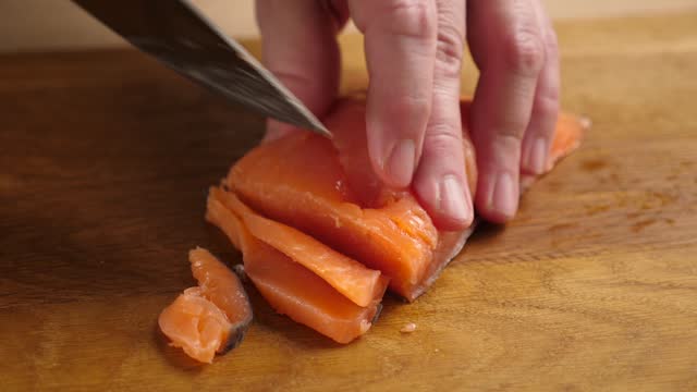 Cut the salmon into pieces with a knife. Cooking dishes from red fish. Slow motion.