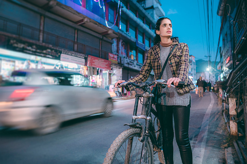 For sustainable living, a young woman rides a bicycle in the evening while commuting after work in the 15-minute city of Himachal Pradesh.