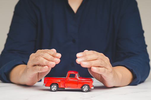 Auto Insurance concept. Businessman hands protection of a red car mockup on a table while sitting at the table. Business finance and road safety