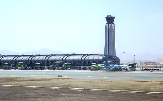 Muscat airport control tower. Oman Air planes at the boarding gates of the airport in Muscat. Sultanate of Oman