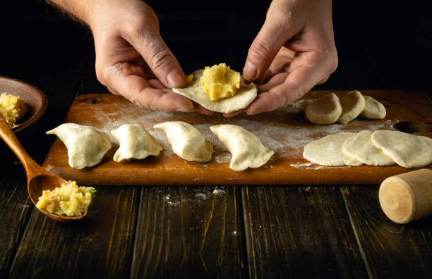 istock Modeling dumplings by the hands of a chef. The concept of preparing dumplings on the kitchen table from dough and boiled potatoes for a delicious breakfast 1949672995