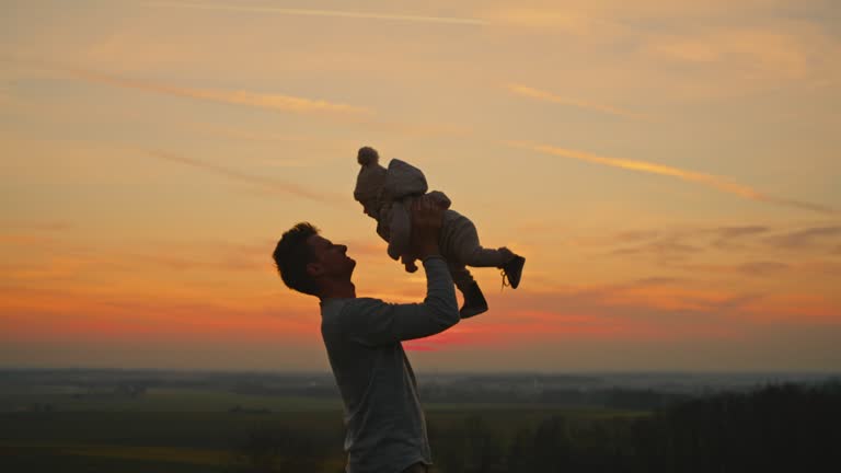 SLO MO Embracing the Sunset Glow: A Father's Tender Embrace with Her 6-Month-Old Baby in the Tranquil Backyard