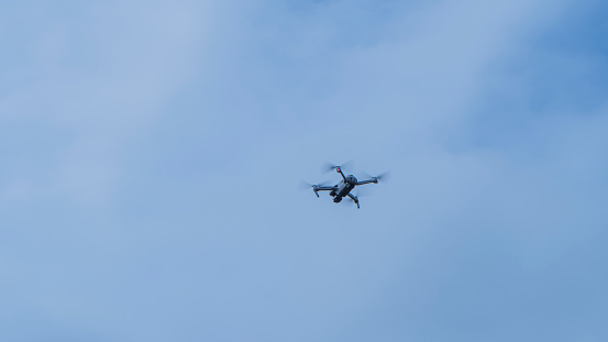 image taken in Chile, January 2024. drone in the air with clouds in the background on a sunny day. the main element in the image is the drone. the drone is flying but in stationary  position, not moving. the image orientation is horizontal. the main element is located in the right third of the image.