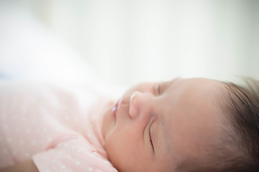 Close up Newborn Baby face Newborn Baby Girl sleeping on cozy bed Infant mixed race baby get sweet dream and good sleeping until morning