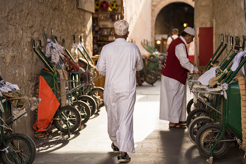 Doha, Qatar - April 22,2023: Local people in traditional attire in old bazaar market Souk Waqif.