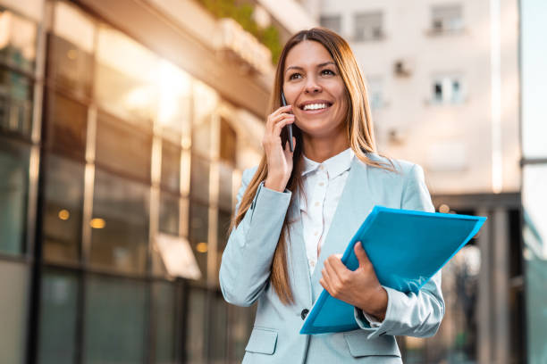 istock A smiling female financial advisor talking on a cellphone and walking with a folder with files in her hand 1949802018